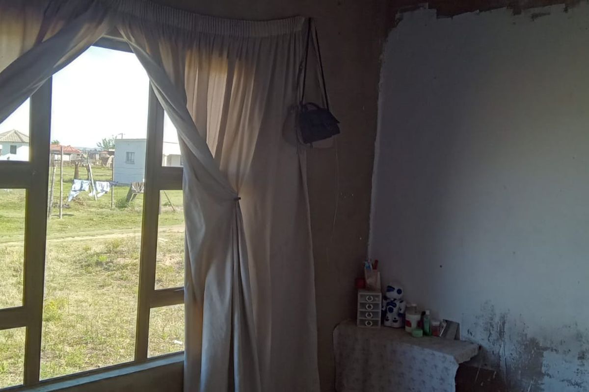 A bedroom interior featuring an aluminium window frame, requiring significant wall finishing and plaster repairs to improve the overall condition.