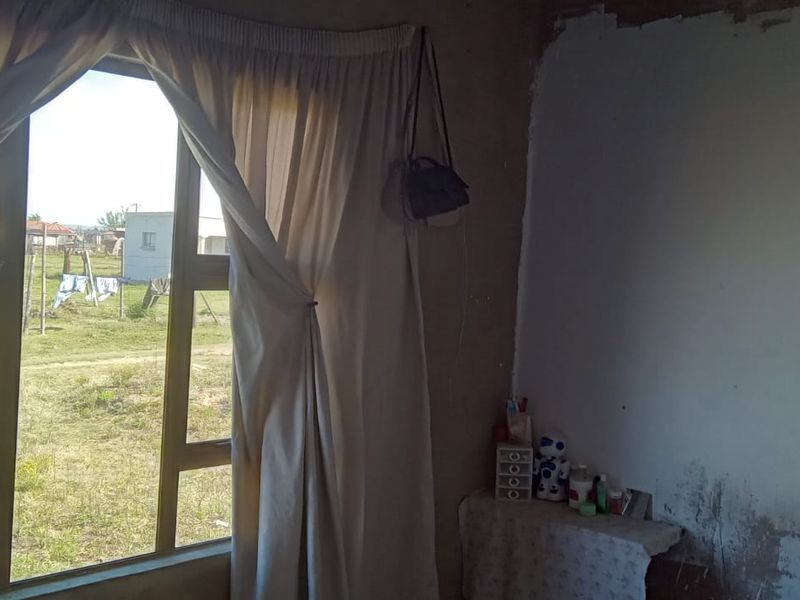 A bedroom interior featuring an aluminium window frame, requiring significant wall finishing and plaster repairs to improve the overall condition.