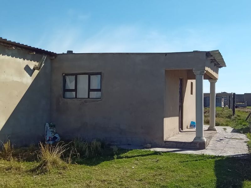 Front view of a single-story house featuring a covered porch with concrete columns and unfinished exterior wall surfaces.