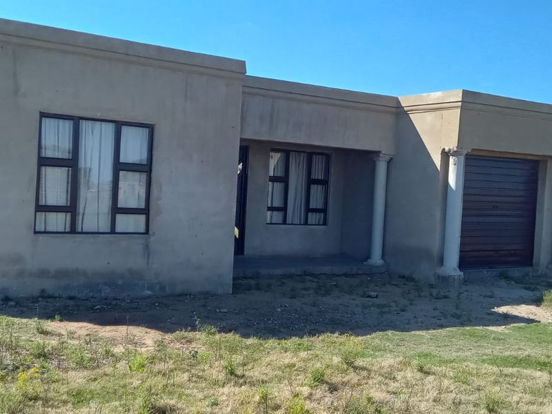 Front elevation of a single-story house featuring a garage, covered entrance with columns, and unfinished exterior plaster finish.