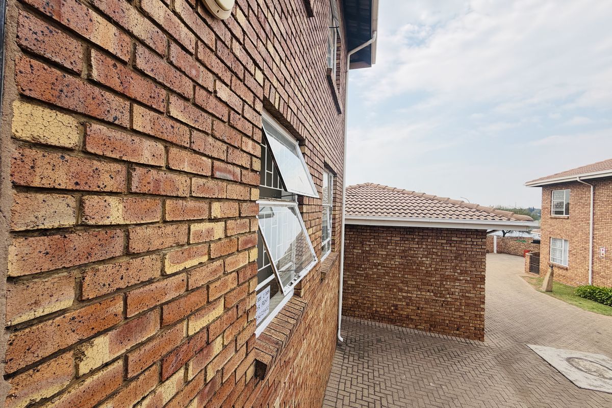 Exterior view of the face brick apartment building showing paved driveway access and tiled roof structures.