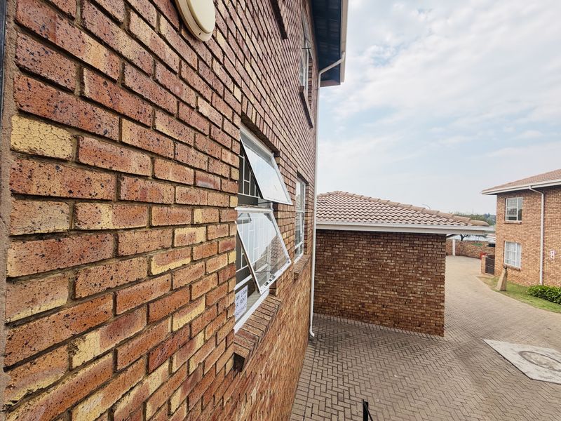 Exterior view of the face brick apartment building showing paved driveway access and tiled roof structures.