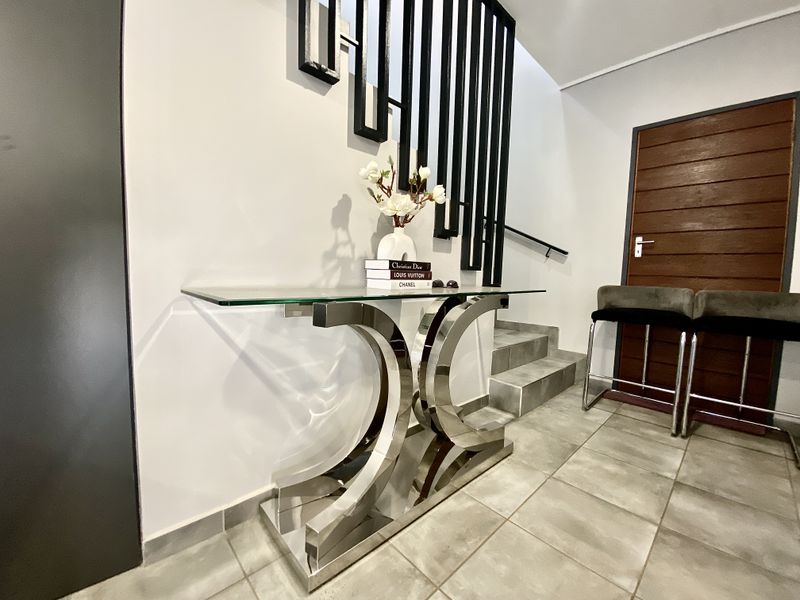 Modern entrance hall featuring tiled flooring, a contemporary staircase with a metal balustrade, and a solid timber door.
