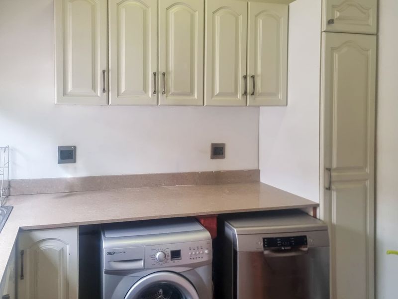 A functional laundry area featuring built-in cabinetry, ample countertop space, and dedicated plumbing connections for appliances.