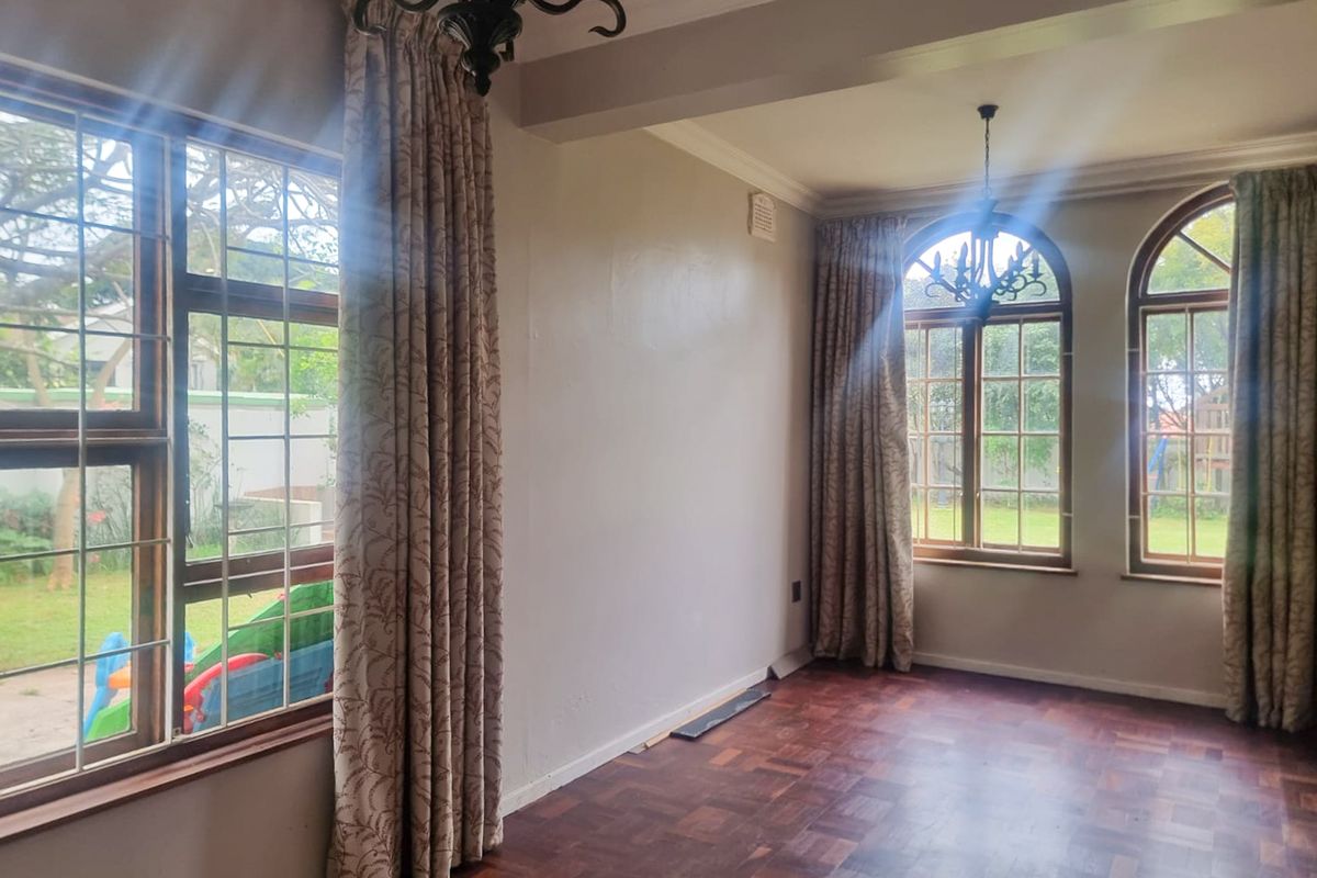 Spacious living area featuring classic parquet flooring, elegant arched windows, and decorative crown molding, offering a bright and versatile space for interior design.