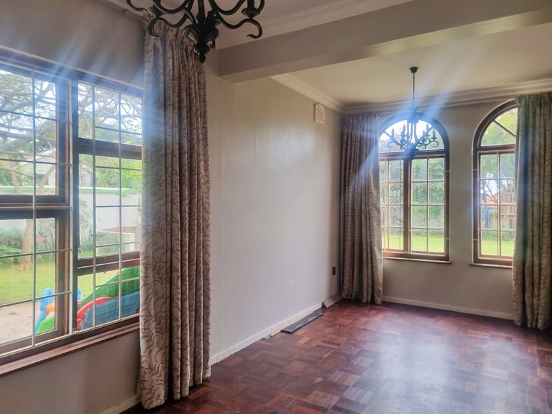 Spacious living area featuring classic parquet flooring, elegant arched windows, and decorative crown molding, offering a bright and versatile space for interior design.