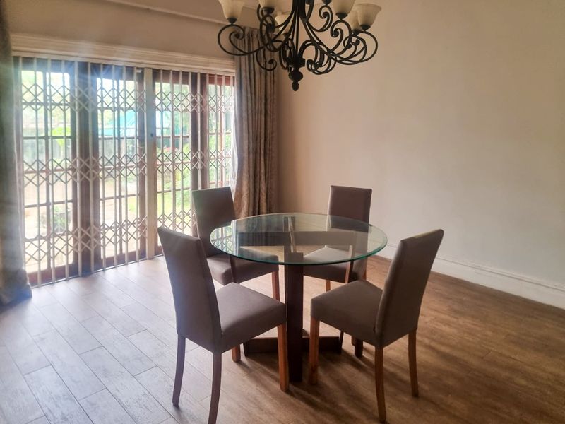 Dining area featuring wood-look tile flooring, a decorative wrought iron chandelier, and sliding glass doors with security gates leading to the exterior.