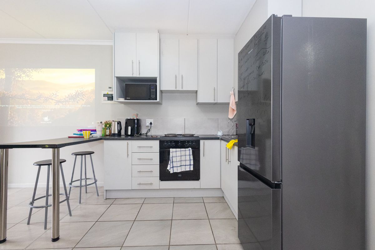 A functional kitchen featuring white cabinetry, dark countertops, a breakfast bar, and integrated appliances with tiled flooring.