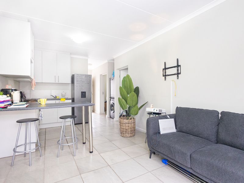 Open-plan living area featuring a functional kitchen with built-in cabinetry, a breakfast bar, and tiled flooring throughout the space.