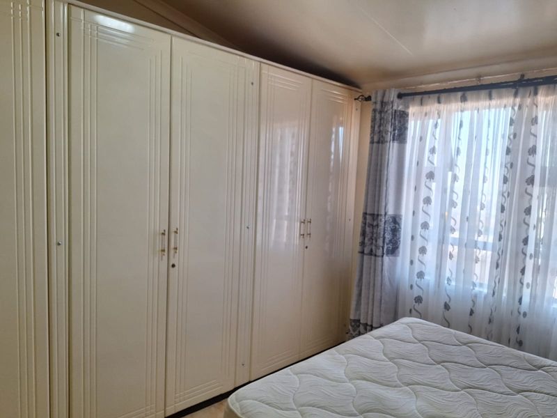 A bedroom featuring extensive built-in cupboards providing ample storage space and a window with installed curtain rods.
