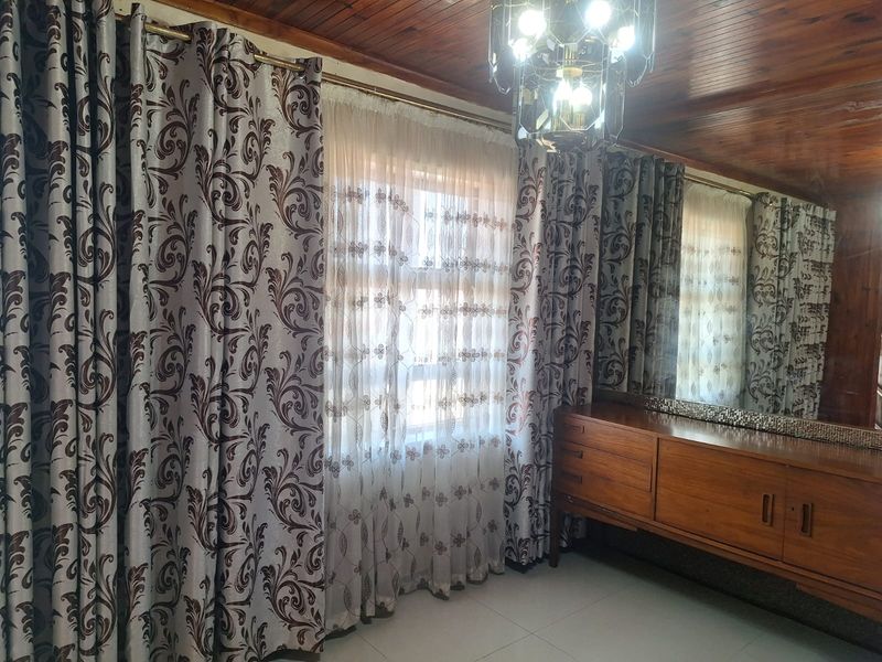 Living area featuring a timber-paneled ceiling, tiled flooring, and a large built-in wall mirror.