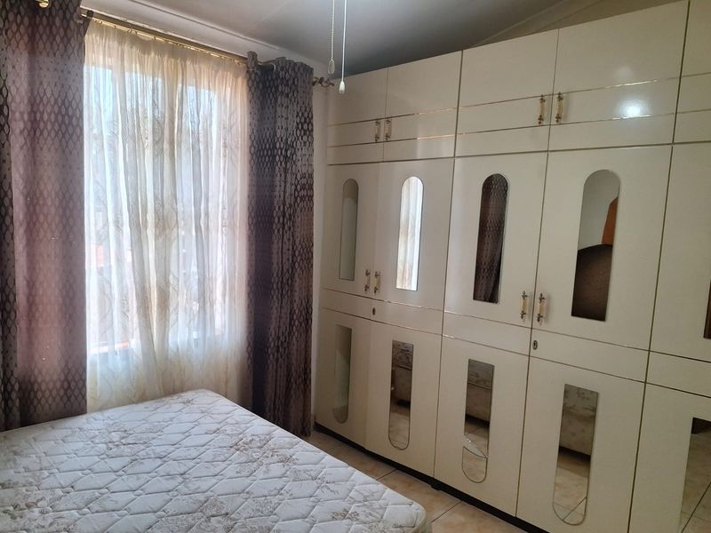 A bedroom featuring extensive built-in cabinetry with integrated mirror panels and tiled flooring, providing ample storage space.