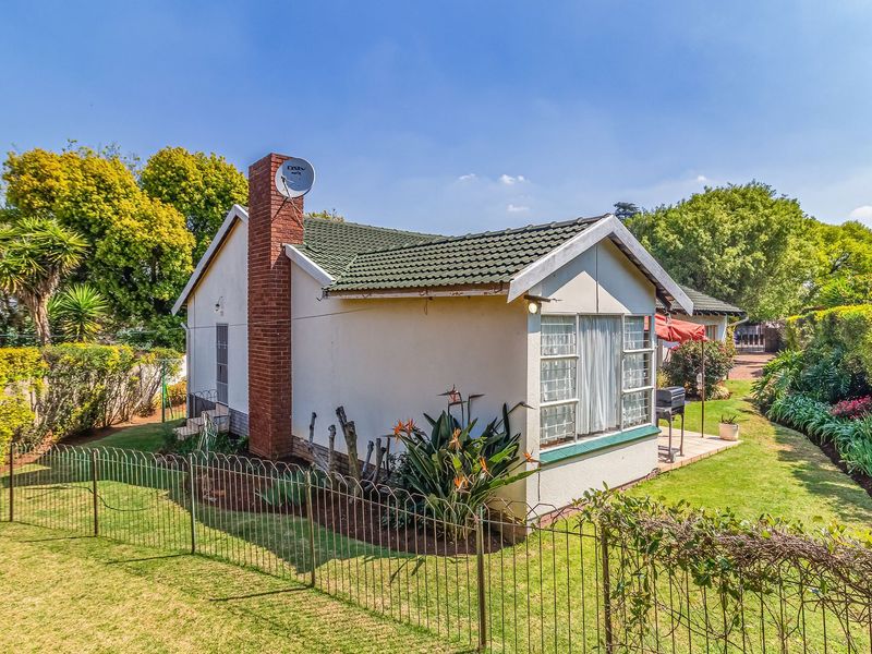 Rear view of the house featuring a brick chimney, tiled roof, and a paved patio area overlooking the garden.