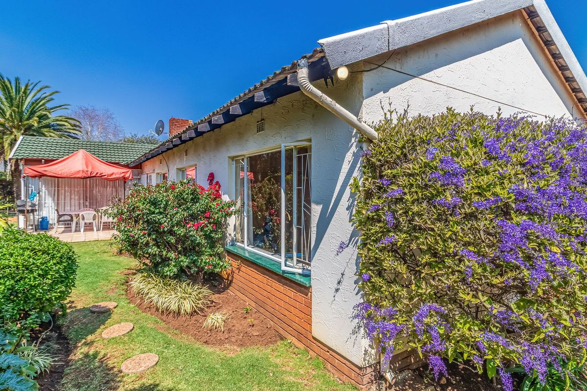 A view of the rear exterior of the house featuring a well-maintained garden, brick base, and tiled roof with guttering.