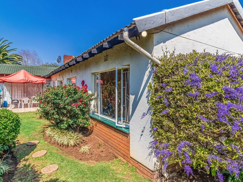A view of the rear exterior of the house featuring a well-maintained garden, brick base, and tiled roof with guttering.