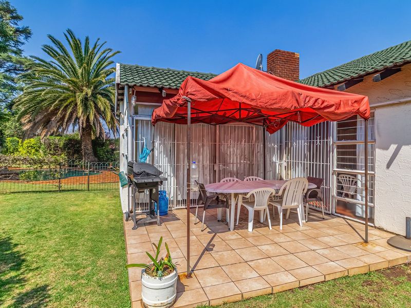 A paved outdoor patio area featuring security gates and access to the rear garden and pool area.