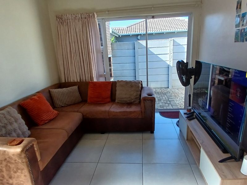 A comfortable living room featuring tiled flooring and a sliding glass door that provides direct access to the outdoor area.