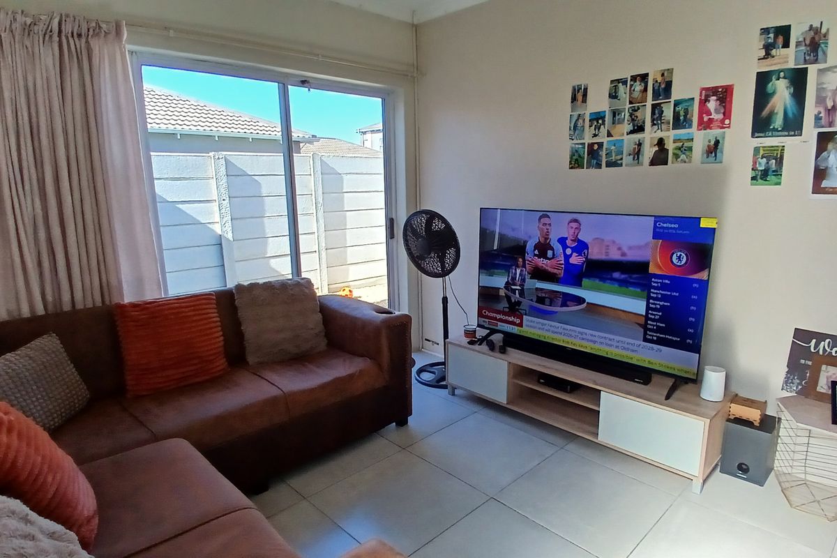 A functional living room featuring tiled flooring and a large sliding glass door that provides access to the outdoor area.