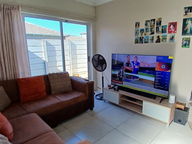 A functional living room featuring tiled flooring and a large sliding glass door that provides access to the outdoor area.