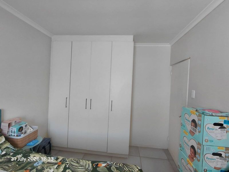 A bedroom featuring built-in cupboards, tiled flooring, and coved ceiling details, providing a functional space with neutral wall finishes.