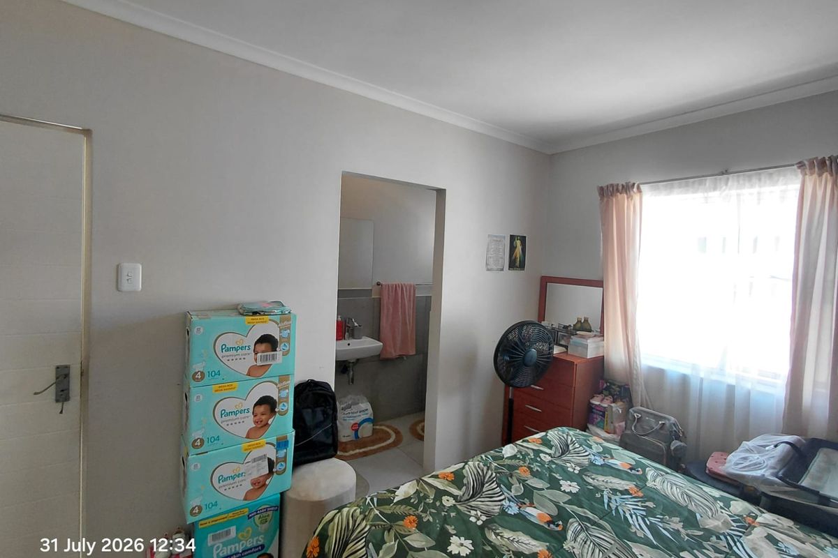 A bedroom featuring an en-suite bathroom access point, neutral wall finishes, and a window with curtaining.