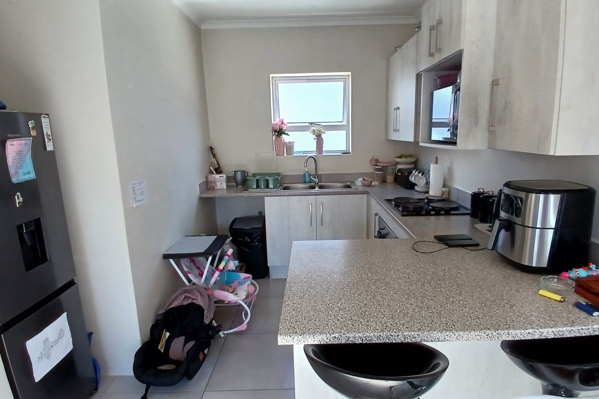 A functional kitchen featuring built-in cabinetry, laminate countertops, a stainless steel sink, and integrated cooking appliances with tiled flooring.
