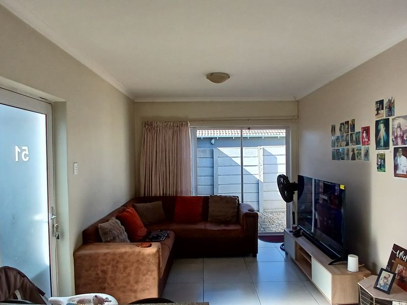 A living room featuring tiled flooring, a sliding glass door leading to the exterior, and a frosted glass entrance door.