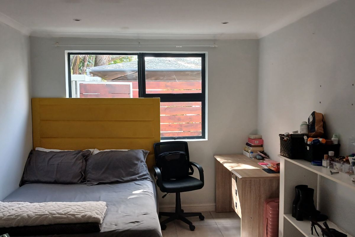 A functional bedroom featuring tiled flooring, recessed downlighting, and a large window providing natural light.