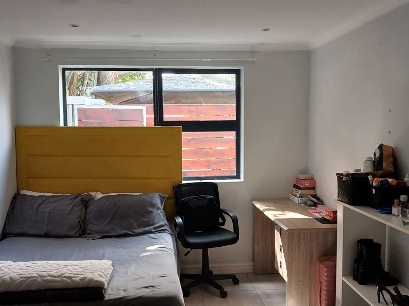 A functional bedroom featuring tiled flooring, recessed downlighting, and a large window providing natural light.