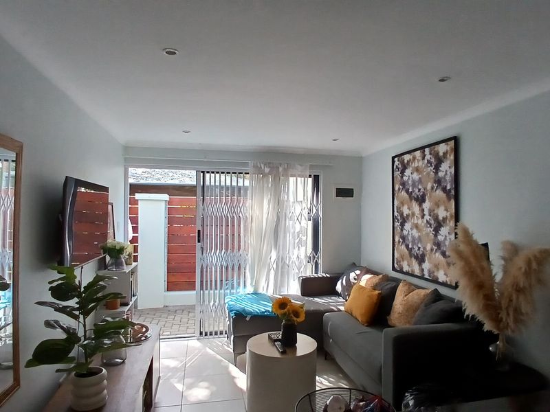 A bright living room featuring tiled flooring, recessed downlights, and a sliding glass door providing access to an outdoor patio area.