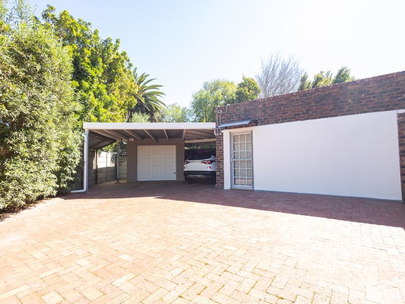 Front exterior view featuring a brick paved driveway, a covered carport, and a secure garage entrance.