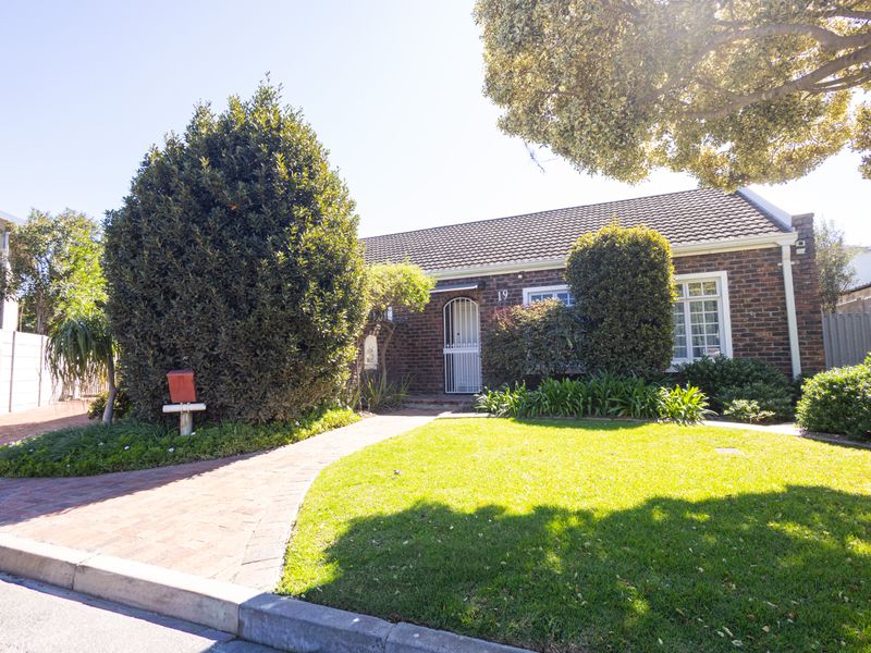 A charming single-story brick house featuring a well-maintained front garden, paved walkway, and secure entrance.