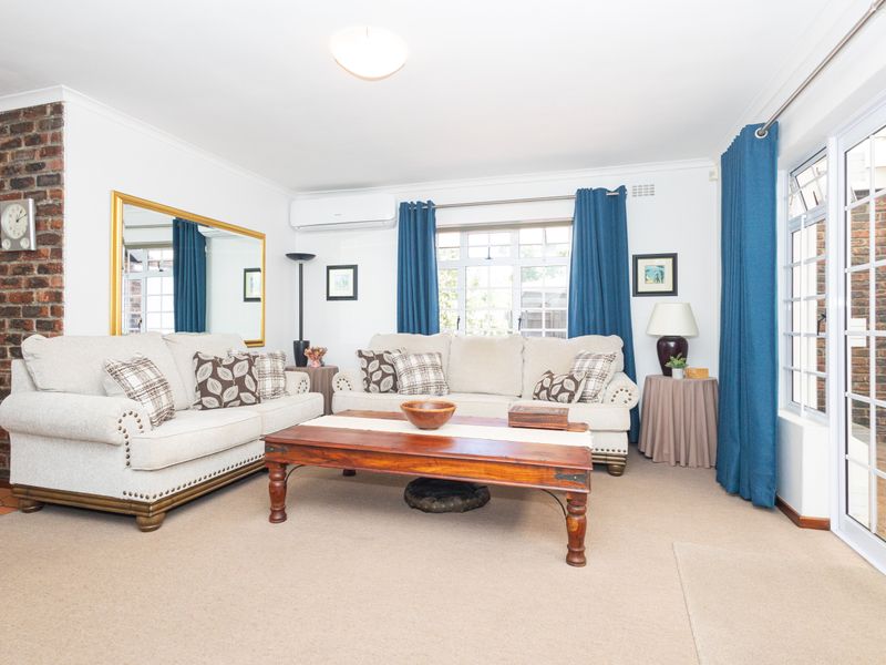 A bright living room featuring a brick fireplace, split-system air conditioning, and sliding glass doors providing access to the outdoor area.