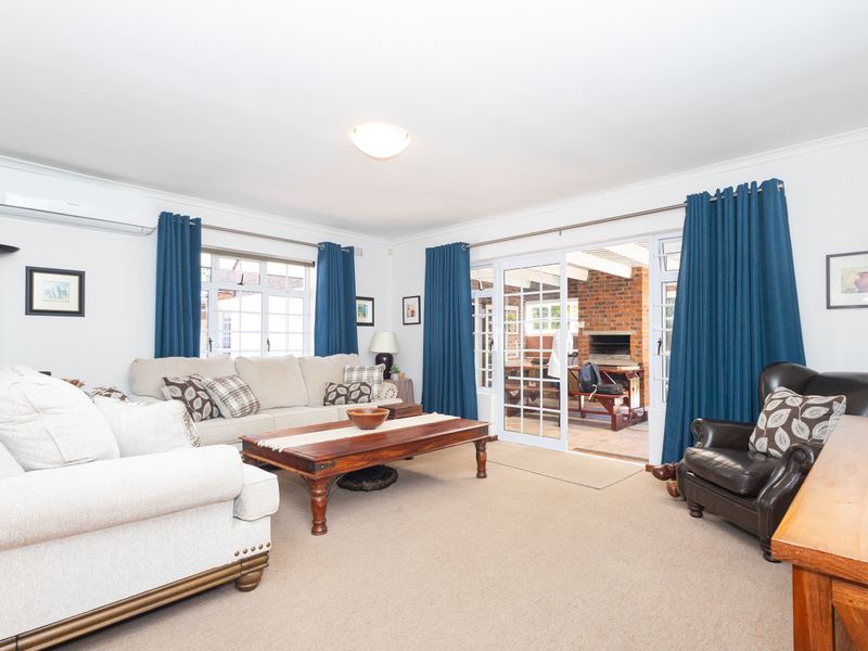 Spacious living room featuring neutral carpeting, coving, and large sliding glass doors that provide seamless access to the outdoor patio area.