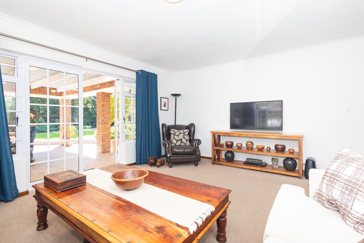 A bright living room featuring carpeted floors and large sliding glass doors that provide direct access to the outdoor patio area.