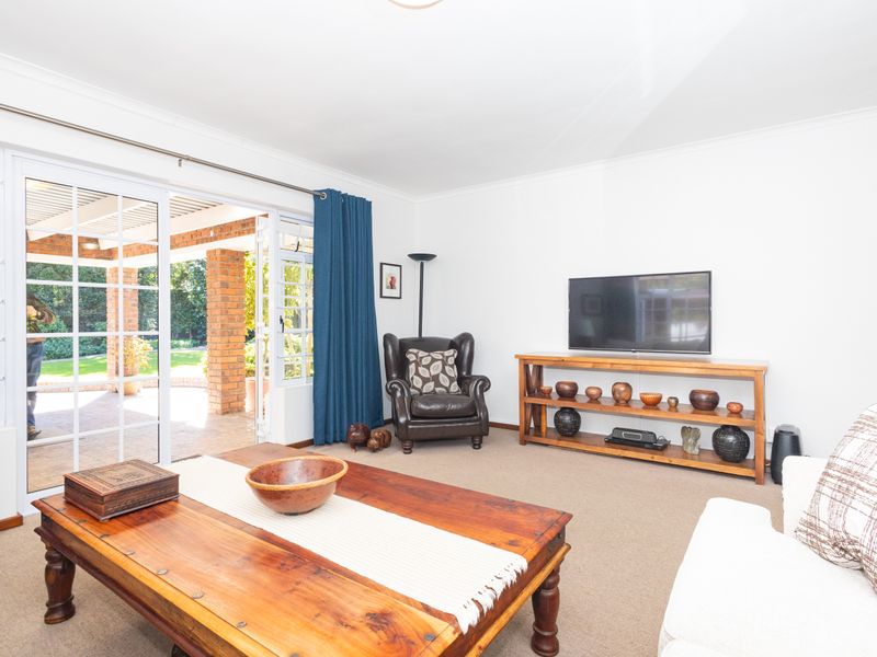 A bright living room featuring carpeted floors and large sliding glass doors that provide direct access to the outdoor patio area.