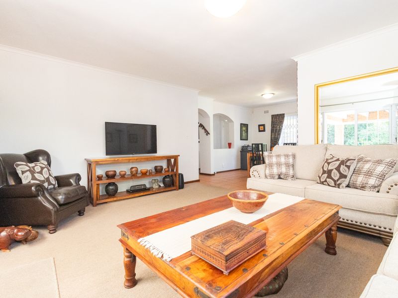 Spacious open-plan living area featuring neutral walls, a mix of carpet and tile flooring, and a decorative archway leading to adjacent spaces.