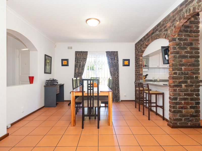 Open plan dining area featuring ceramic tile flooring and a distinctive exposed brick archway leading into the kitchen space.