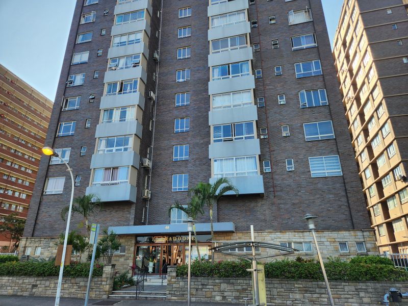 Front elevation of a multi-story brick apartment building featuring stone cladding at the base and integrated balcony structures.