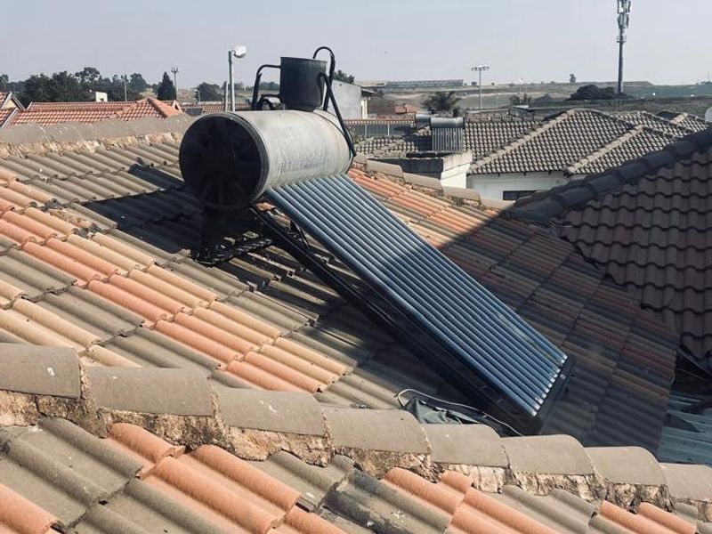 A view of the property roof featuring a solar water heating system installed on terracotta-style roof tiles.