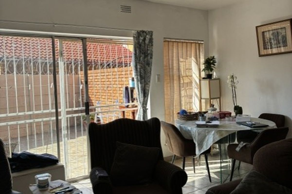 A living room area featuring ceramic floor tiles, a textured ceiling, and a sliding glass door providing access to the outdoor space.