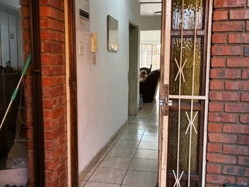 Entrance area featuring exposed brick exterior, a security gate, and tiled flooring leading into the interior hallway.