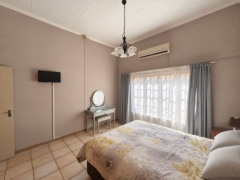 A bedroom featuring tiled flooring, an air conditioning unit, and a ceiling light fixture, with some visible signs of wear on the ceiling and walls.