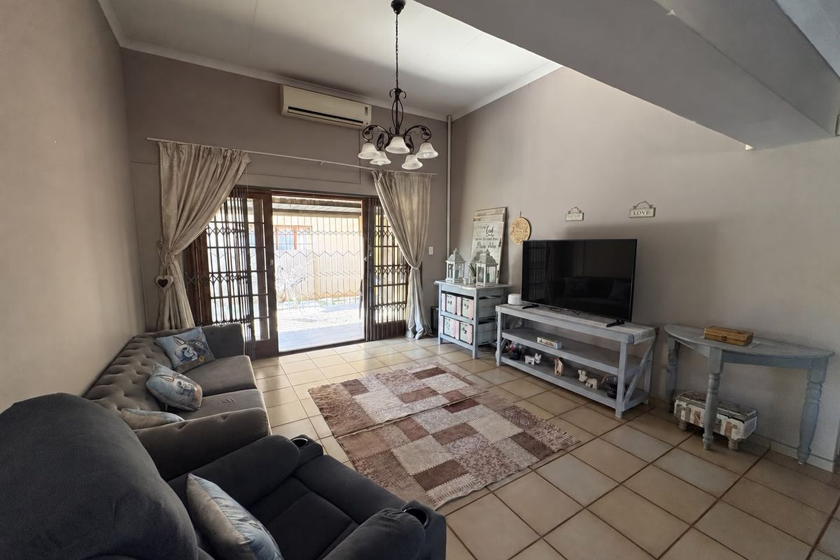 A spacious living room featuring tiled flooring, an air conditioning unit, and a sliding glass door providing access to the outdoor area.