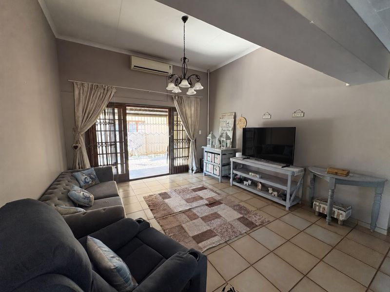 A spacious living room featuring tiled flooring, an air conditioning unit, and a sliding glass door providing access to the outdoor area.