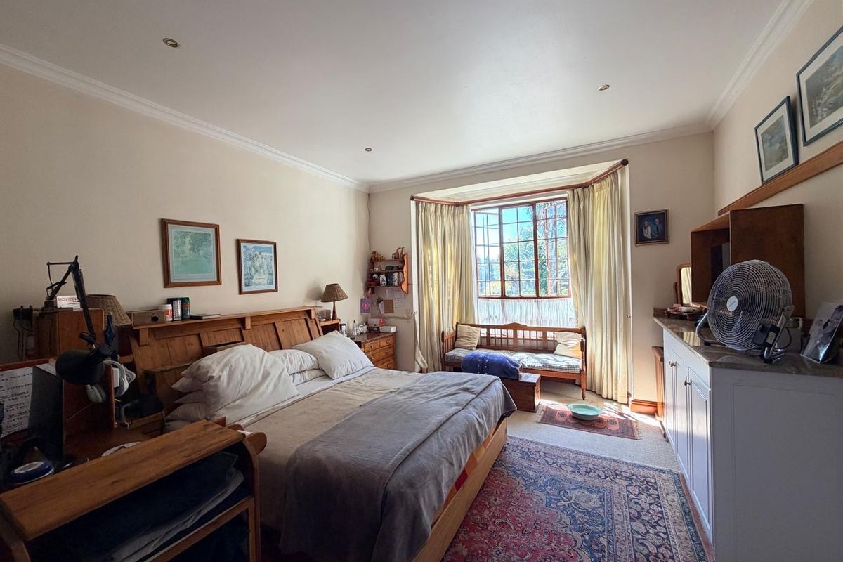Spacious bedroom featuring a large bay window, recessed downlighting, and built-in cabinetry, offering a comfortable and functional living space.