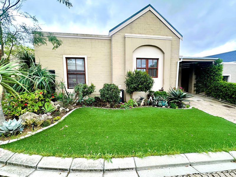 A well-maintained front facade of a house featuring a neat garden, paved driveway, and classic brick exterior architecture.