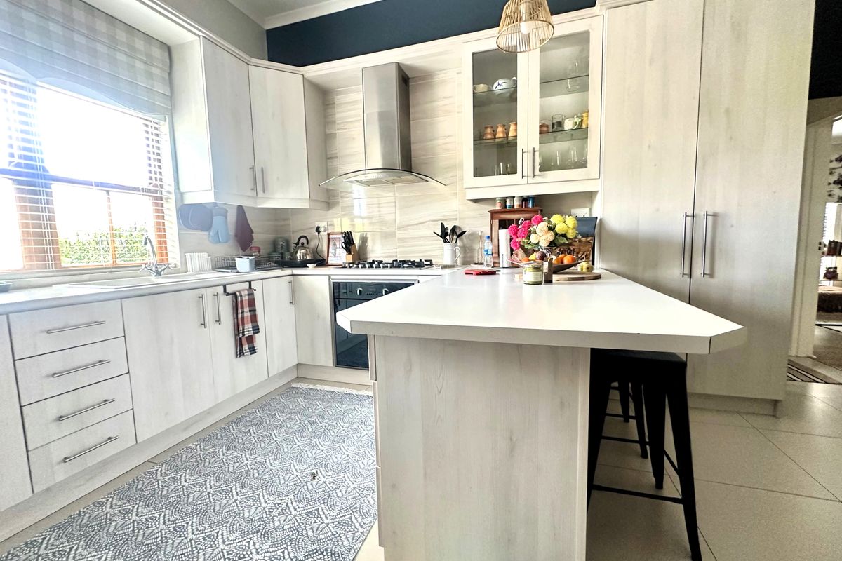 Modern kitchen featuring light wood-grain cabinetry, a central island, stainless steel appliances, and ample storage space with a functional layout.