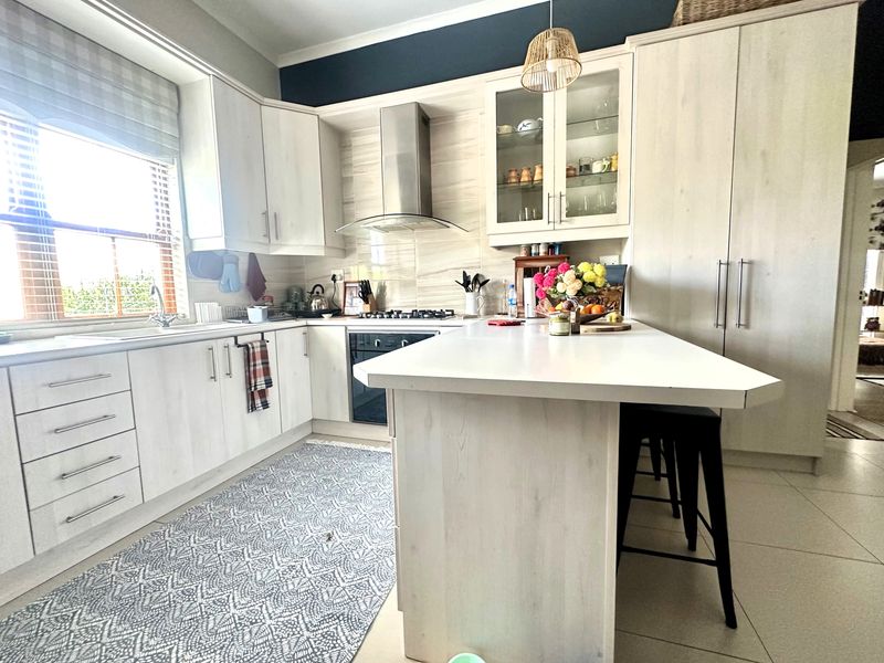 Modern kitchen featuring light wood-grain cabinetry, a central island, stainless steel appliances, and ample storage space with a functional layout.