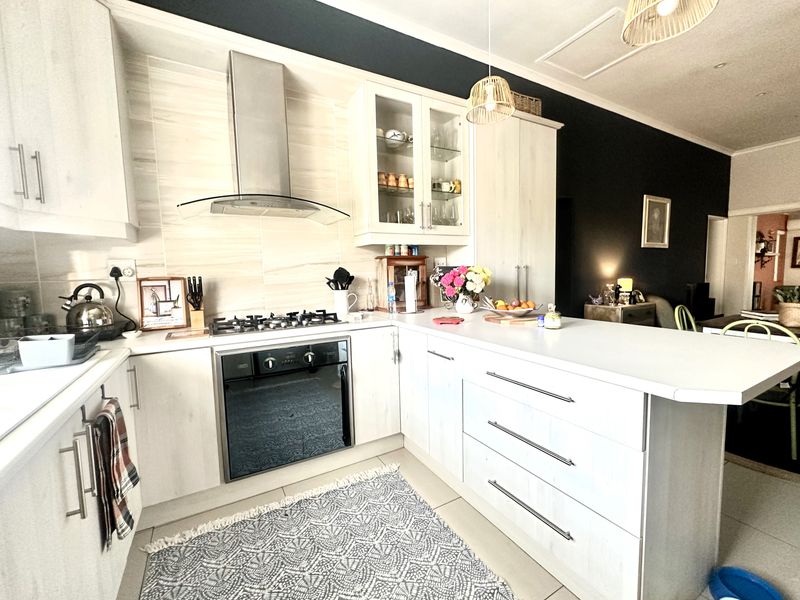 Modern kitchen featuring light wood-finish cabinetry, stone countertops, a gas hob with extractor fan, and a breakfast bar island.